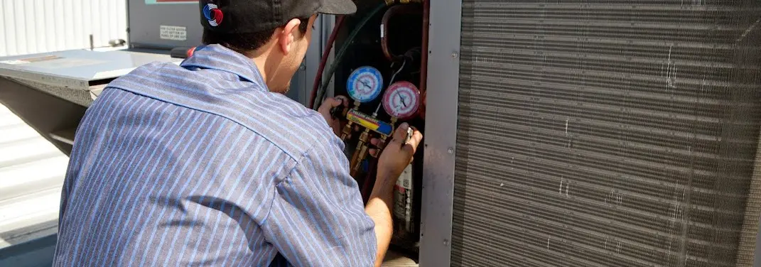 HVAC technician servicing a condenser unit in Marinette